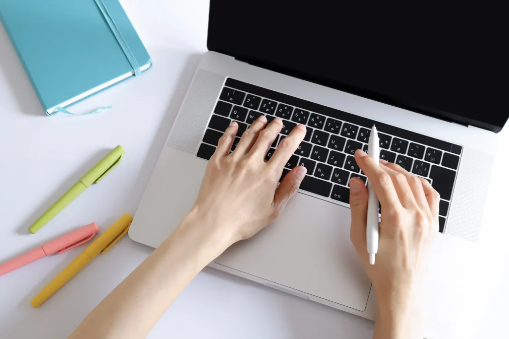 上から見たノートパソコンとタイピングする手