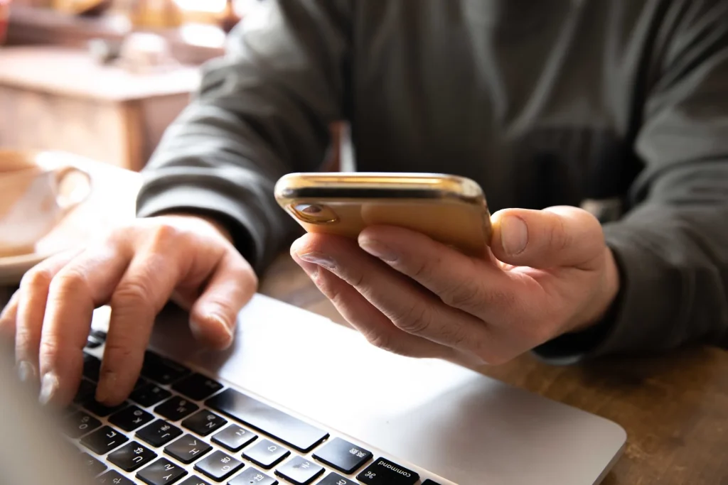 PCとスマートフォンで作業をする男性