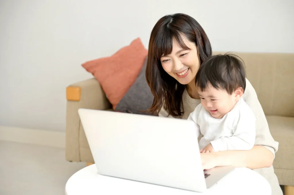 幼児を抱っこしながら笑顔で働く女性